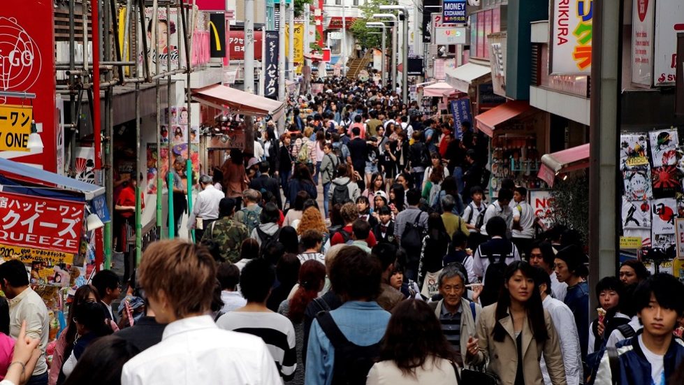 FILE PHOTO – People walk on a street in a busy shopping district in Tokyo